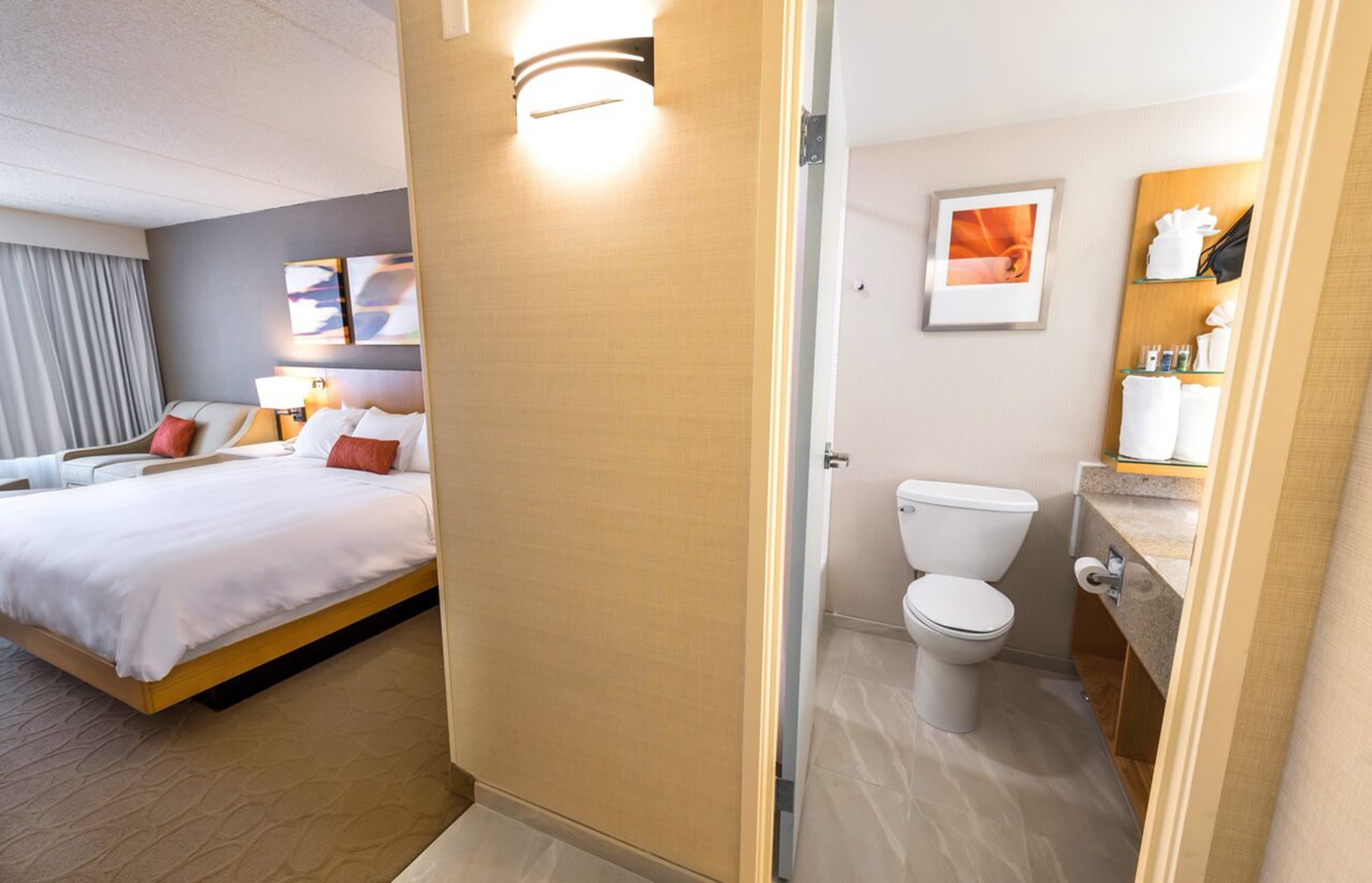 A hotel room with a bed, a bathroom with a toilet and sink, and a shower area.