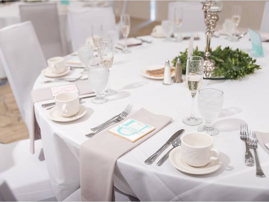 A table set for a formal event with white tablecloths, silverware, and glassware.