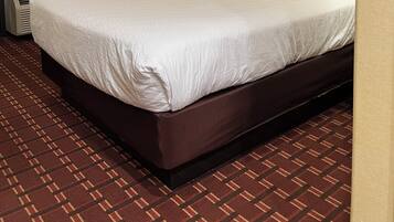 A hotel room with a large bed, a bedside table, a lamp, and a patterned curtain.