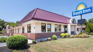 A Days Inn with a red roof, brick facade, and a clear blue sky.