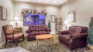A room with a patterned carpet, leather sofas, a wooden coffee table, and framed pictures on the walls.
