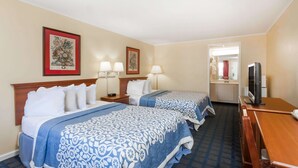 A hotel room with two beds, a TV, and a desk.