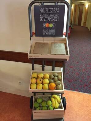 A fruit cart with a sign in French, a tray with papers, and a wooden box with fruits. - ibis Poitiers Centre (Poitiers)