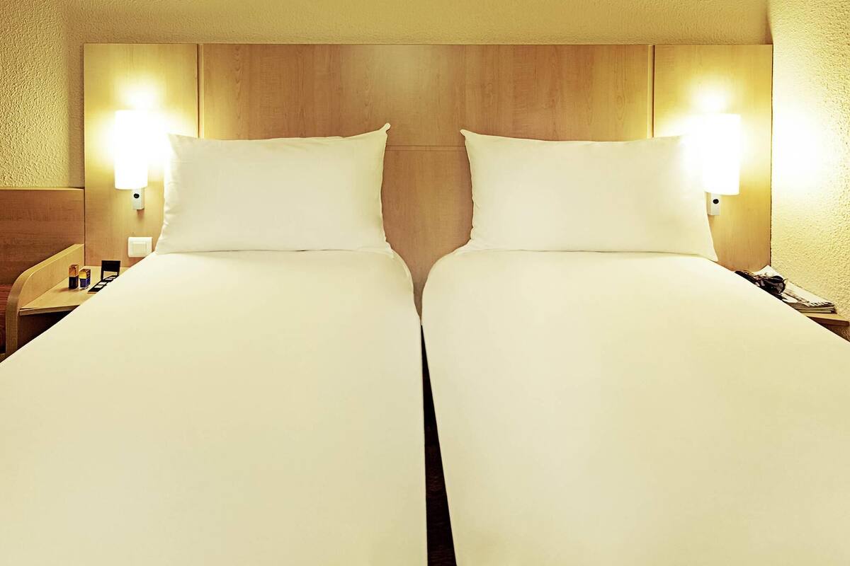 A double bed with a wooden headboard, two bedside tables, and wall-mounted lamps.