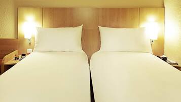 A double bed with a wooden headboard, two bedside tables, and wall-mounted lamps.