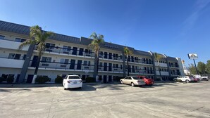 A Days Inn hotel with a parking lot, multiple floors, and palm trees. - Days Inn by Wyndham Ontario Airport (Ontario)