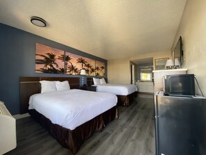 A hotel room with two beds, a painting of palm trees, a kitchenette, and a refrigerator. - Days Inn by Wyndham Ontario Airport (Ontario)