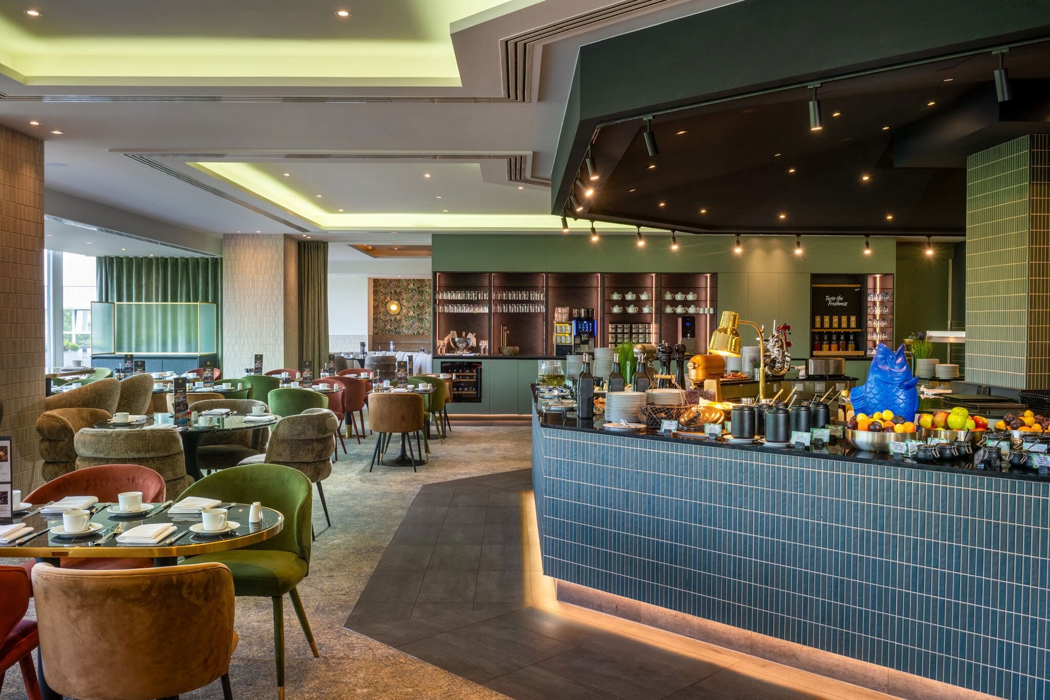 Un restaurante moderno con zona de bar, diferentes disposiciones de asientos y una variedad de alimentos y bebidas a la vista.