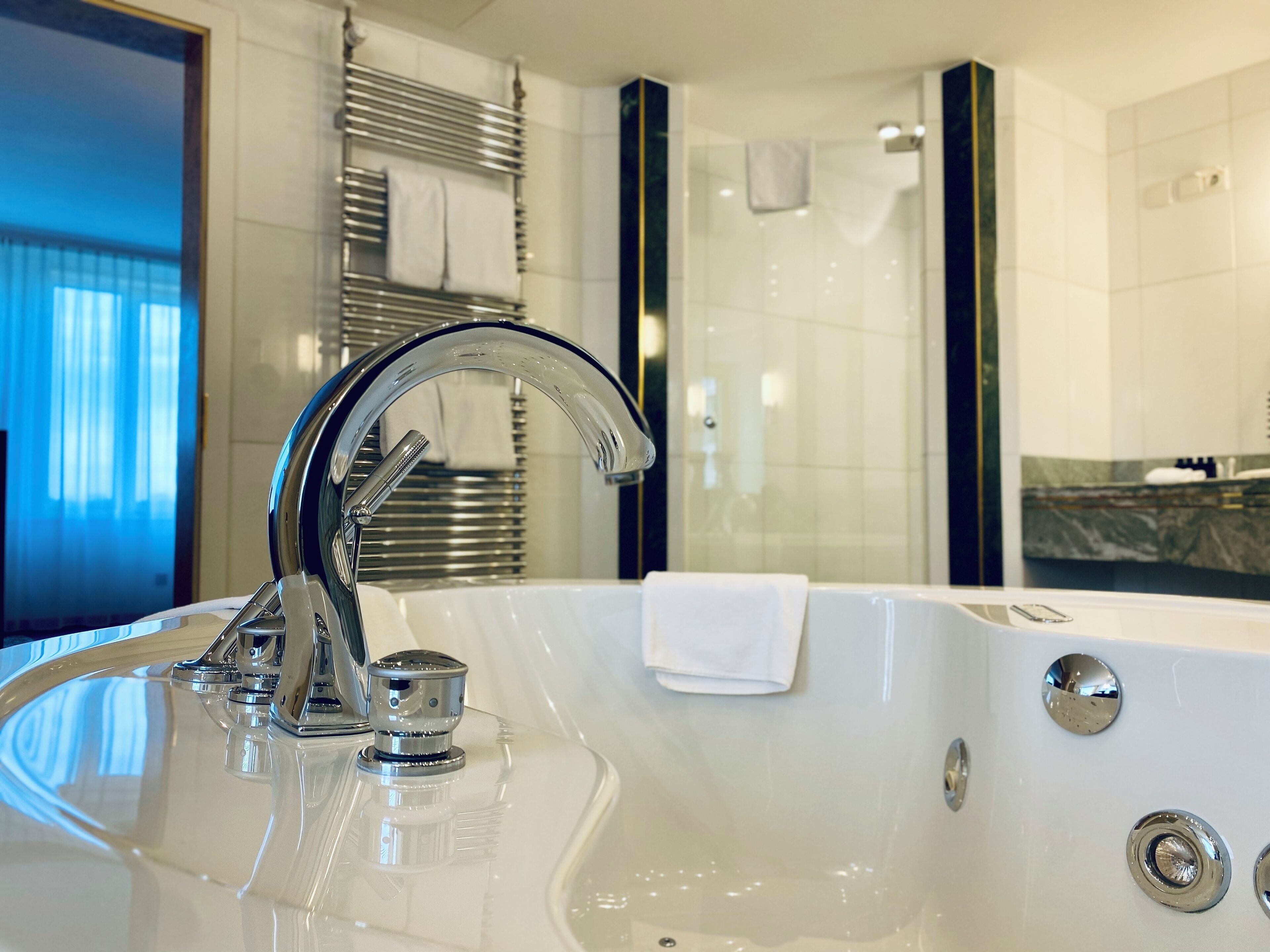 A modern bathroom with a large bathtub, a chrome faucet, and a glass shower enclosure.