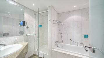 Un baño moderno con ducha acristalada, bañera independiente y tocador de mármol con lavamanos.