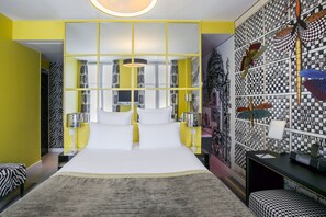 Een moderne slaapkamer met een groot bed, gele wanden en een behang met patroon.