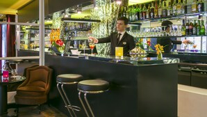 Zona de bar con un cantinero, taburetes y estantes llenos de botellas.