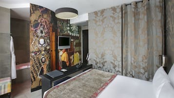 A hotel room with a bed, a TV, a desk, and a bathroom.