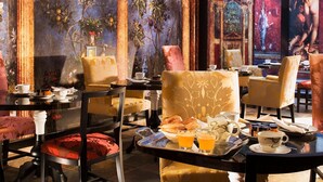 Un comedor con una mesa lista para el desayuno, que incluye bollería, zumo de naranja y té.