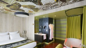 Una habitación de hotel moderna con una cama grande, un baño con bañera y zona de ducha.