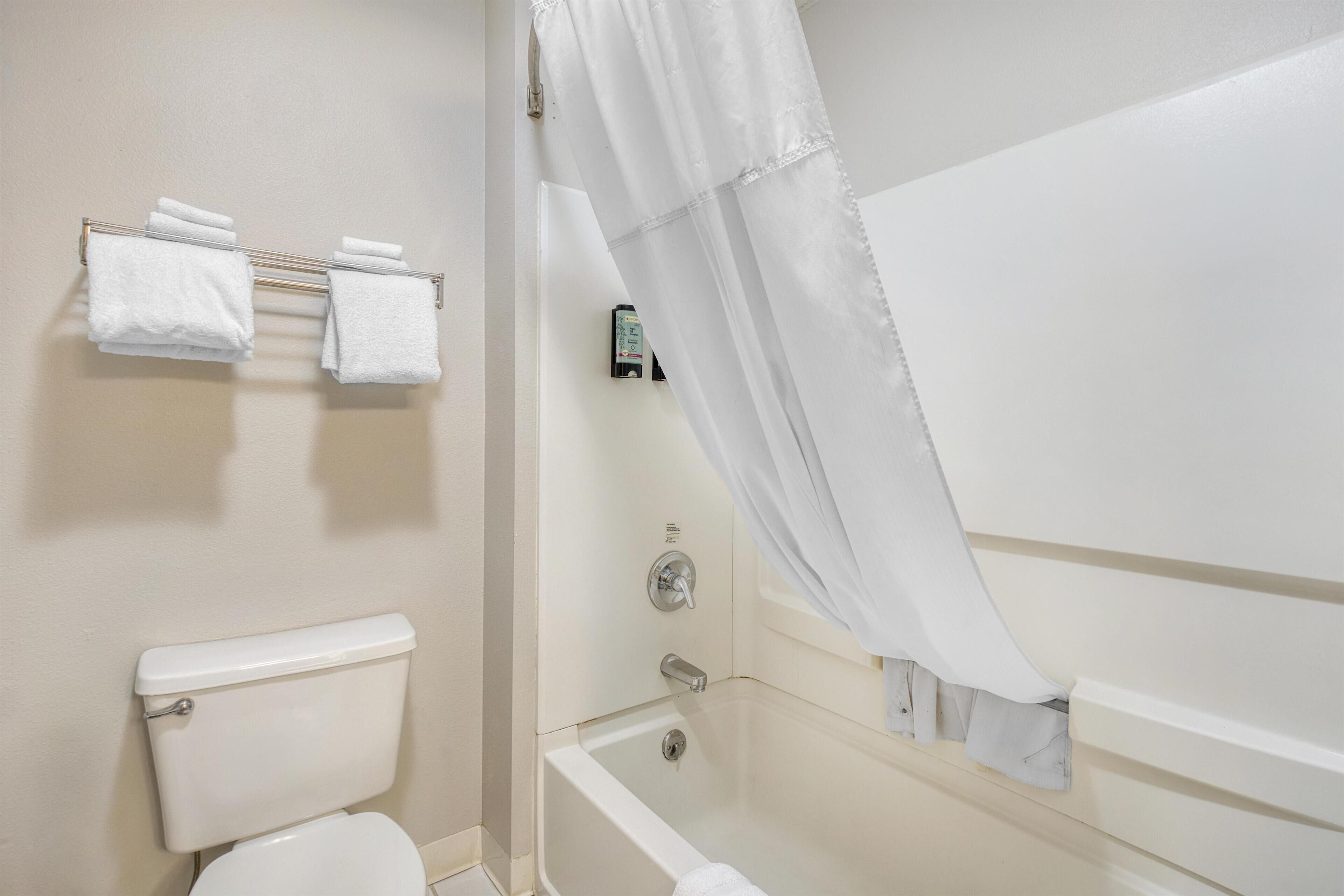A bathroom with a toilet, a bathtub, and a towel rack with towels.