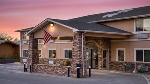 A hotel with a stone facade, an American flag, and a parking lot. - SureStay Plus by Best Western Montrose (Montrose)