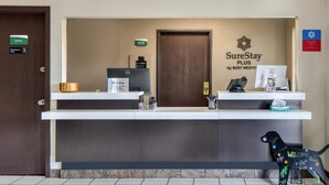 A hotel reception desk with a "SureStay Plus by Best Western" sign, a "Cashier on Duty" sign, a "New Card" sign, and a "Welcome" sign on a dog-shaped decoration. - SureStay Plus by Best Western Montrose (Montrose)