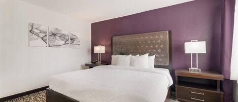 Camera d'albergo con un letto grande, una testiera con motivo decorativo, due comodini con lampade e un tappeto fantasia.