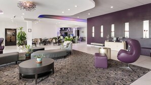 A modern lobby with a curved ceiling, seating areas, and a reception desk. - Clarion Inn & Suites Across From Universal Orlando Resort (Orlando)