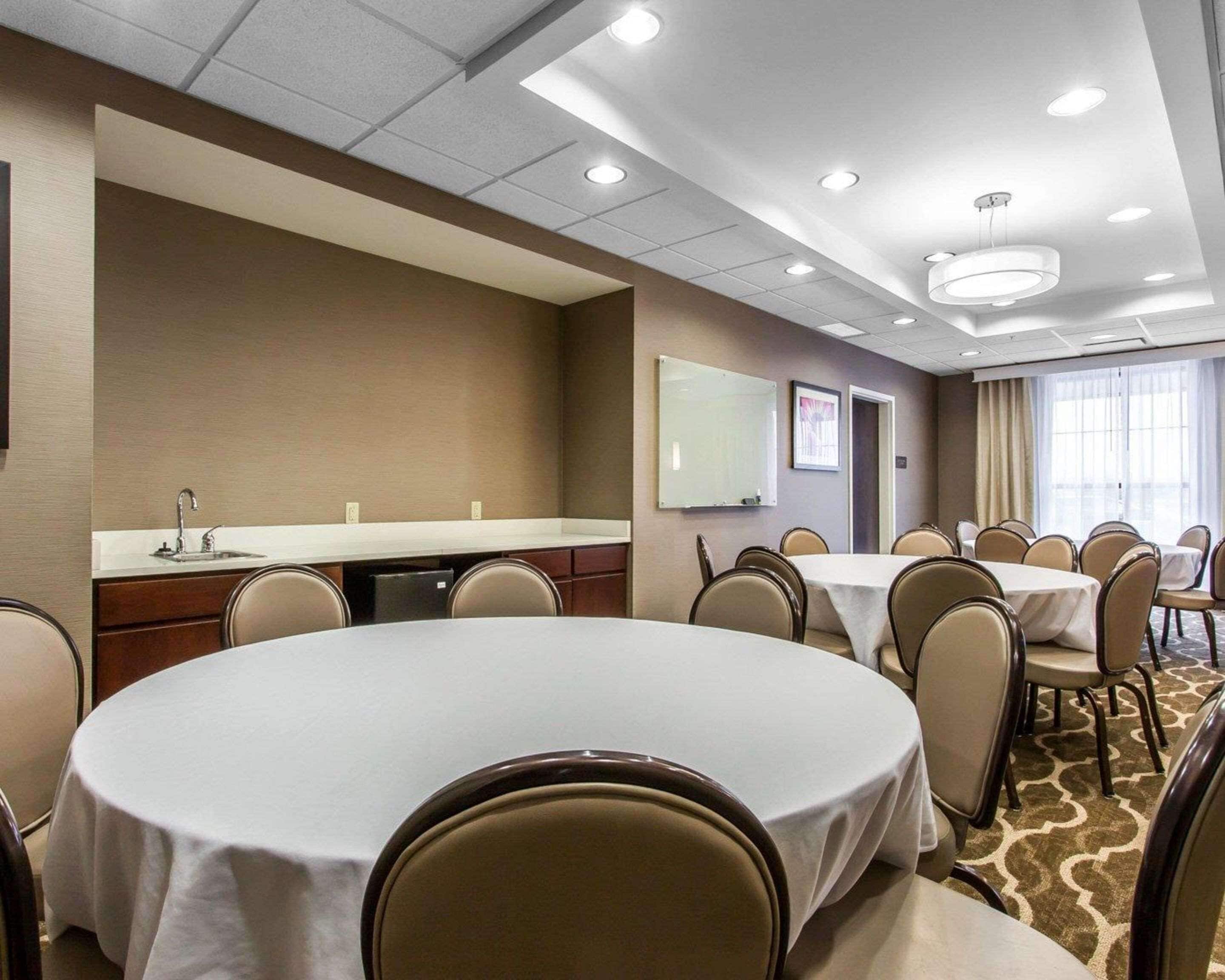 A conference room with a long table, several chairs, a whiteboard, and a television.