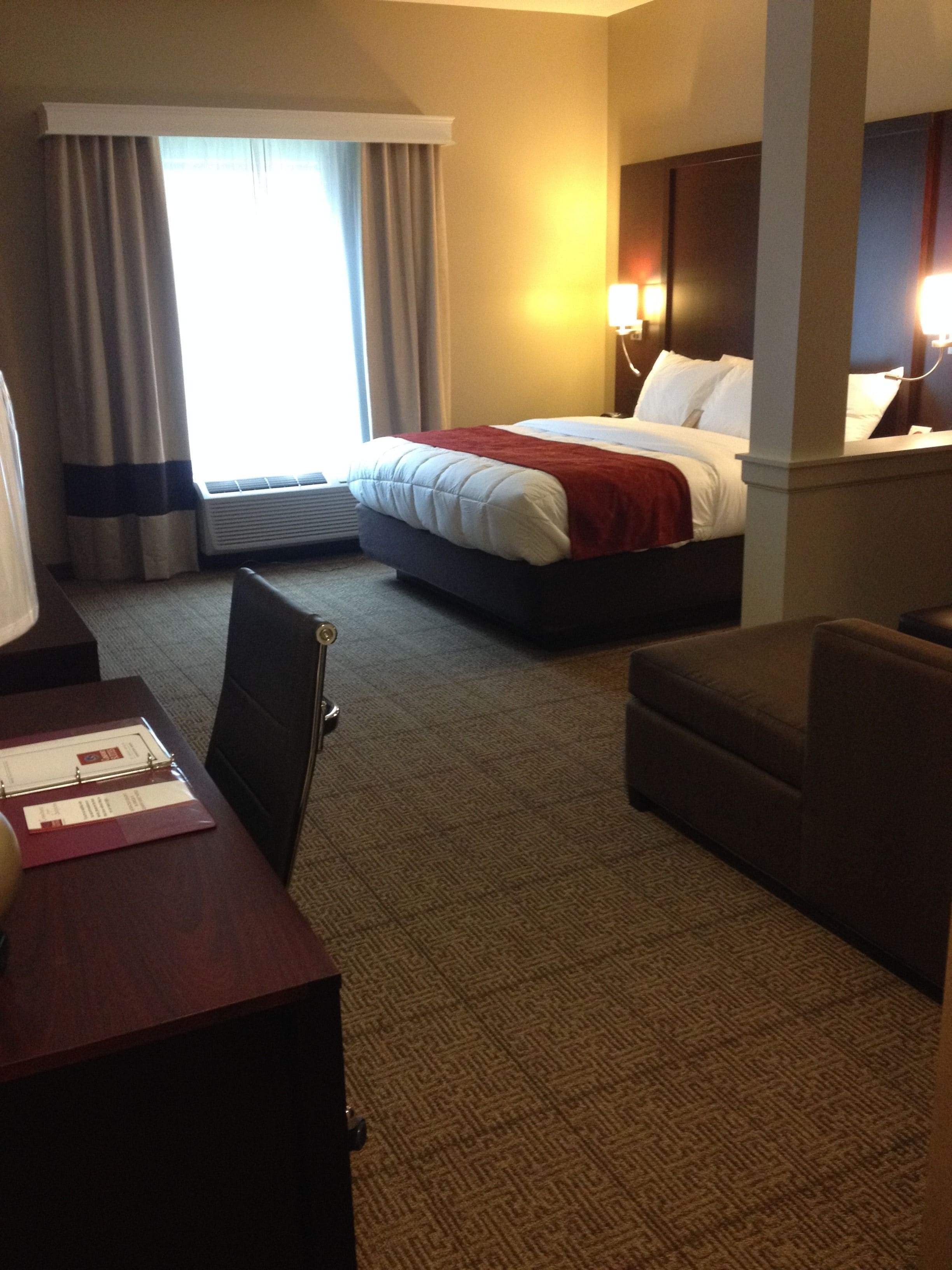 A hotel room with a bed, a desk, a chair, and a nightstand.