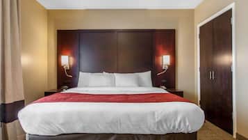 A hotel room with a large bed, two bedside tables, a wardrobe, and two wall-mounted lamps.