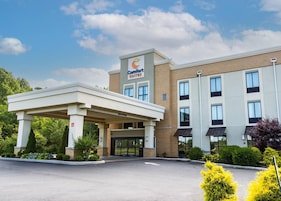 A Comfort Suites hotel with a covered entrance, multiple windows, and a clear sky.