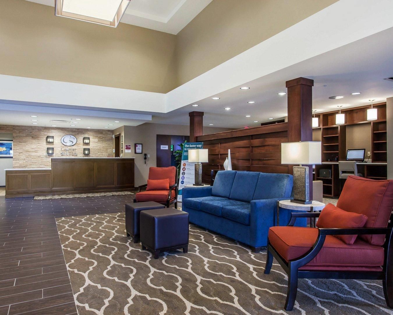 A hotel lobby with a reception desk, seating area, and a large window.