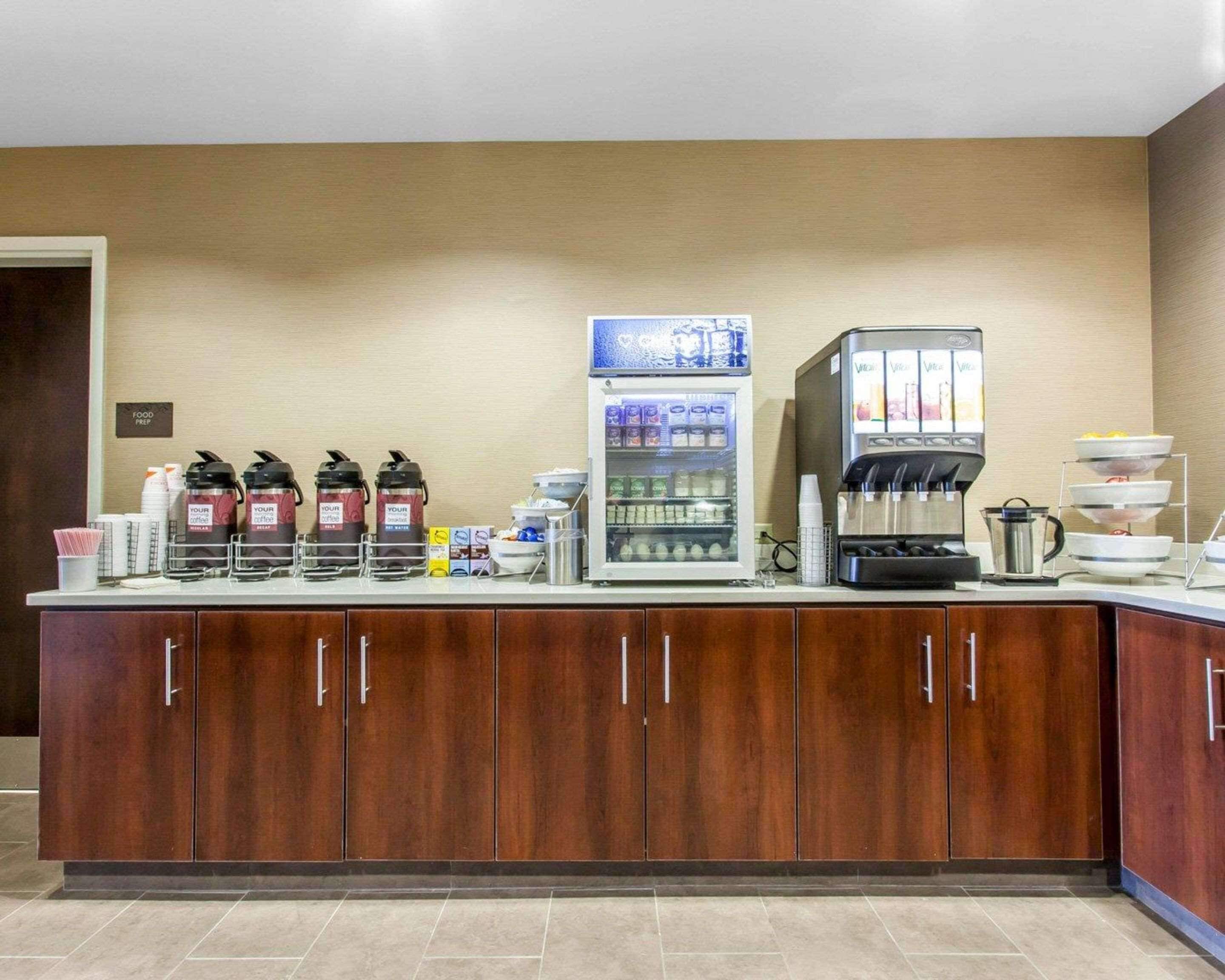 Estación de desayuno autoservicio con cafeteras, dispensador de bebidas refrigeradas y una máquina de café.