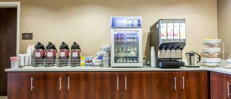 Estación de desayuno autoservicio con cafeteras, dispensador de bebidas refrigeradas y una máquina de café.