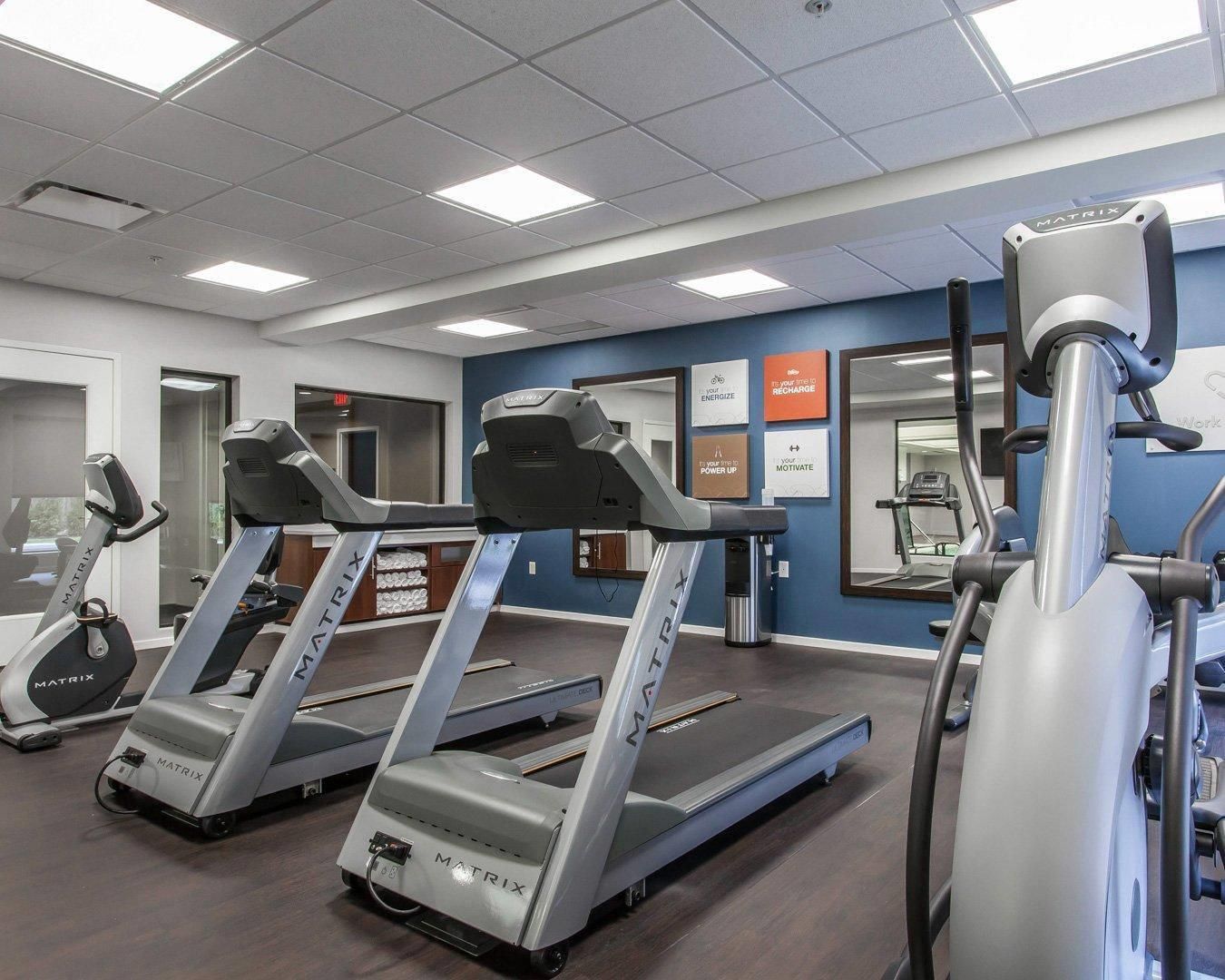 A gym with treadmills and a stationary bike, equipped with motivational posters on the walls.