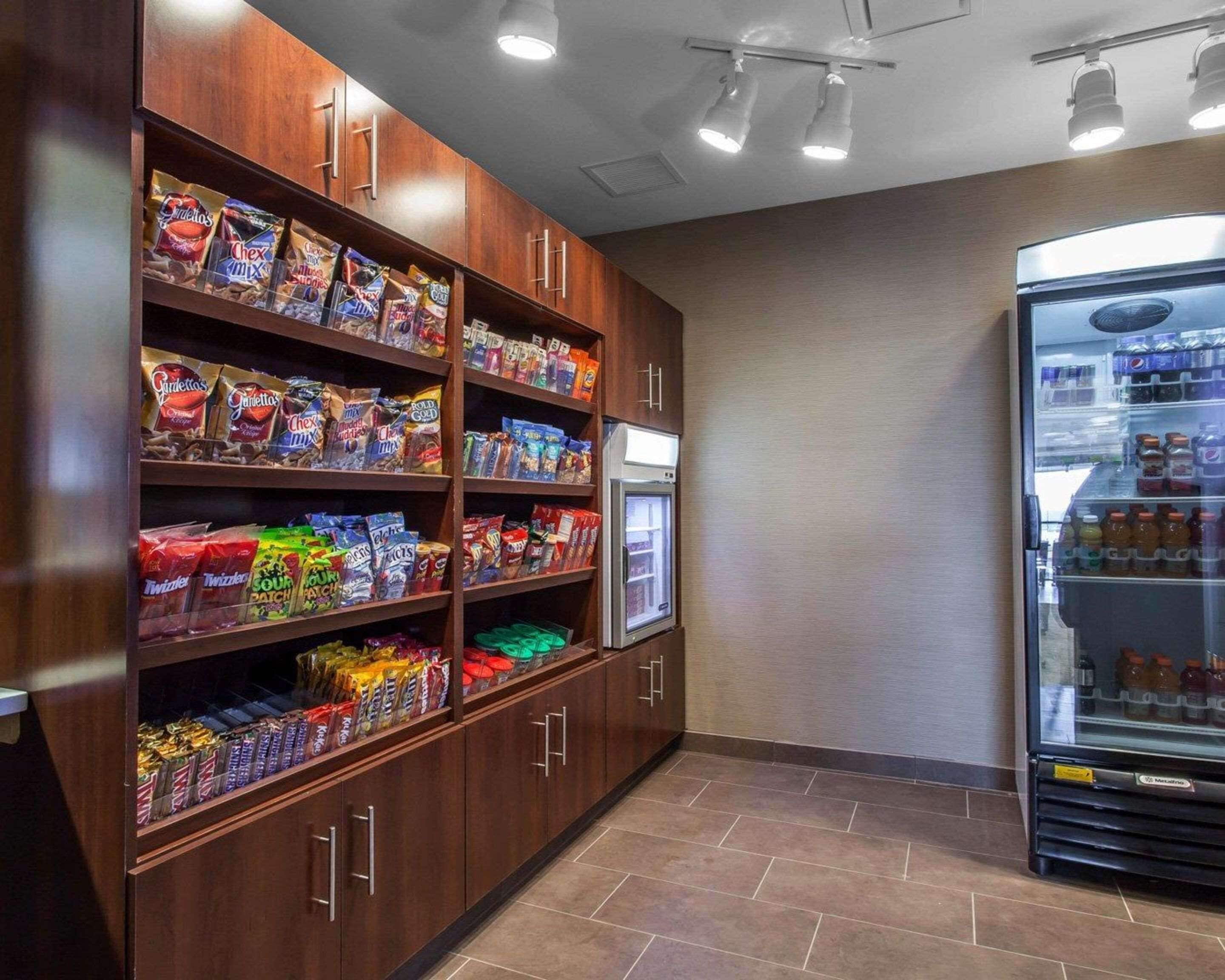 Un área de aperitivos y bebidas con estantes llenos de diferentes opciones y un refrigerador con bebidas.