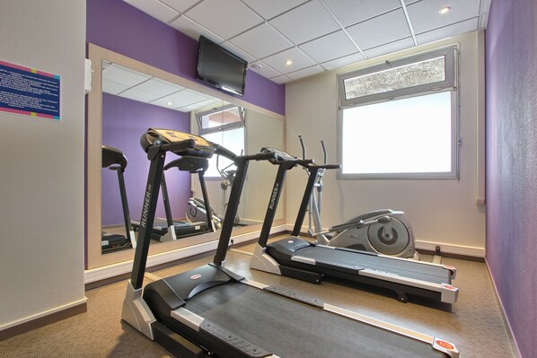 Une salle de sport équipée de tapis de course, d’un vélo d’appartement et d’un miroir.