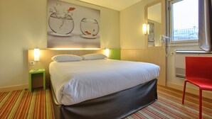 A hotel room with a bed, a green nightstand, a red chair, a large window, and a wall-mounted artwork of fish in water. - ibis Styles Paris Roissy CDG (Roissy-en-France)