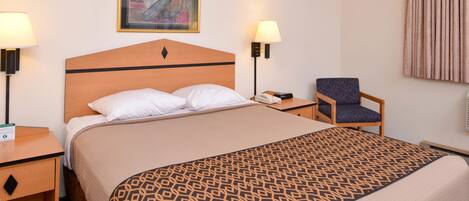Een hotelkamer met een bed, twee nachtkastjes, een stoel, een lamp en een schilderij aan de muur.
