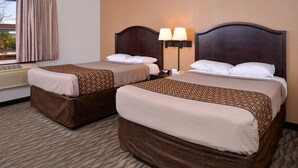A hotel room with two beds, a window with curtains, an air conditioning unit, and a nightstand with a lamp.