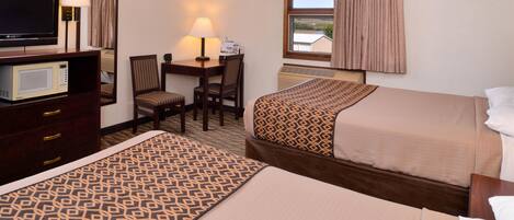 A hotel room with two beds, a desk with a chair, a television, a microwave, and a window with curtains.