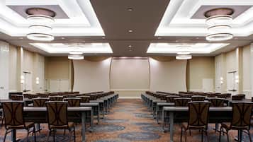 A conference room with rows of chairs, tables, and a carpeted floor.