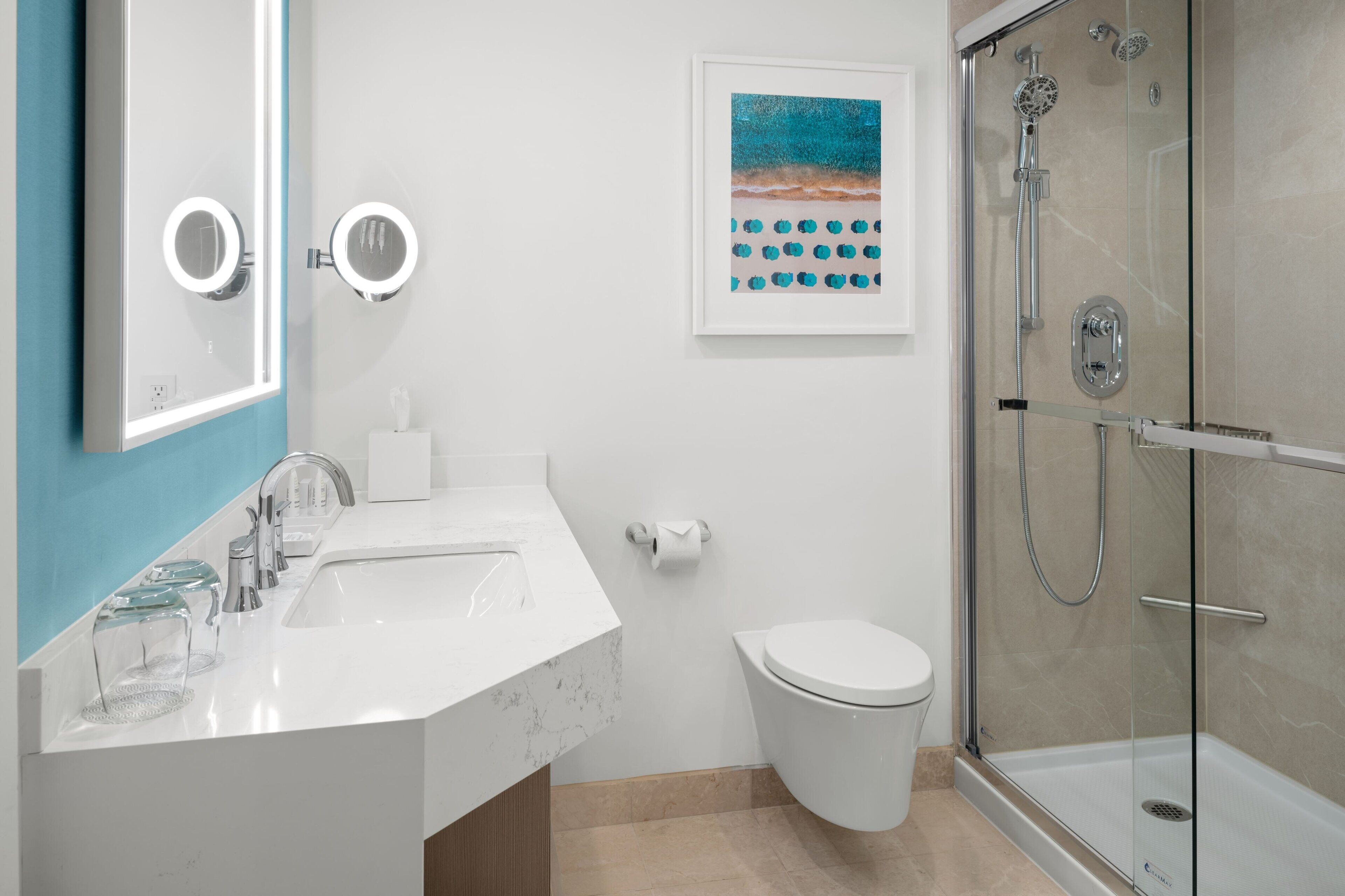 A modern bathroom with a white sink, two round mirrors, a toilet, and a glass-enclosed shower.