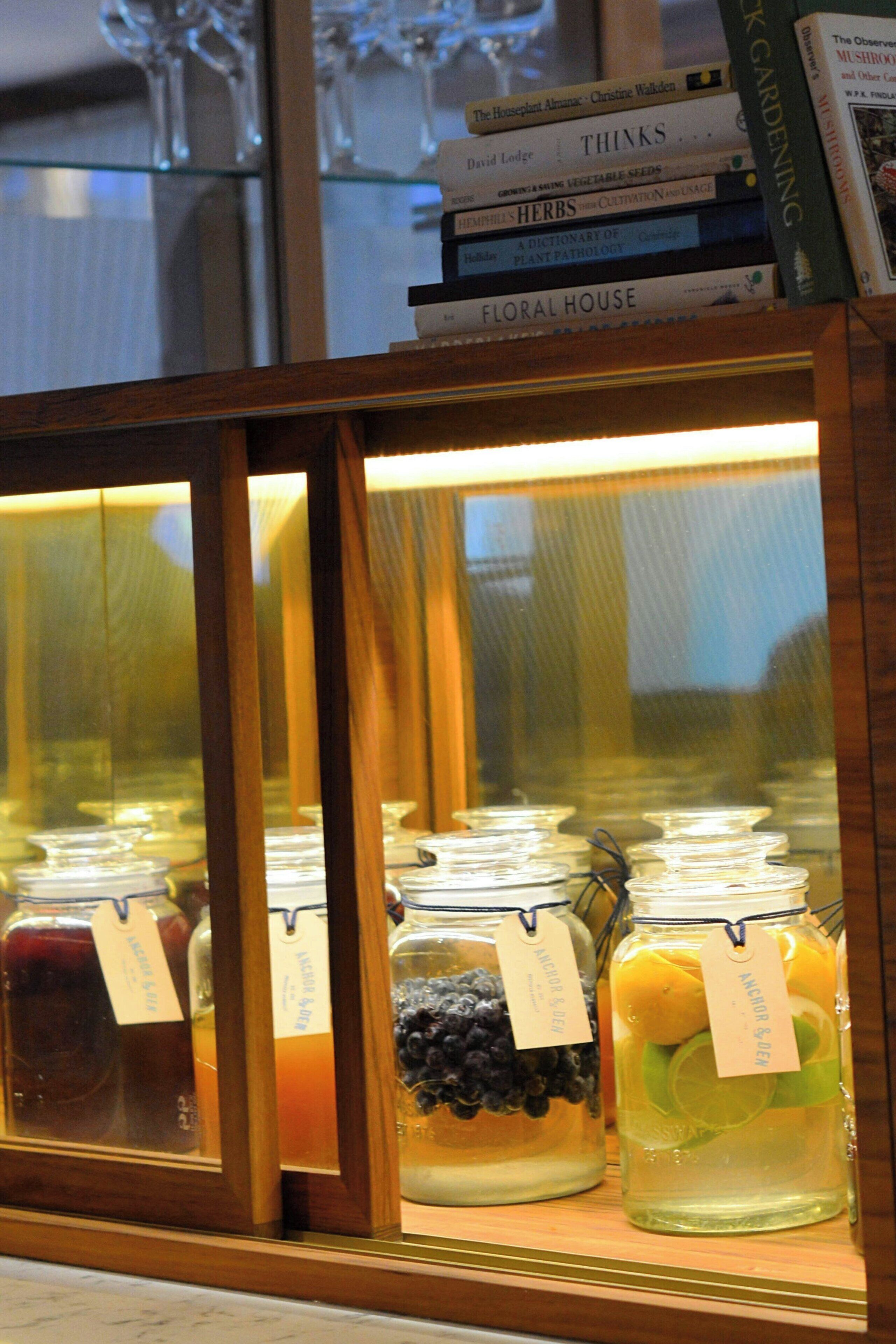 A display case with jars of preserved fruits and vegetables, and a stack of books on top.