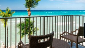 A balcony with wicker chairs overlooking a beach and ocean. - Grand Cayman Marriott Resort (Seven Mile Beach)