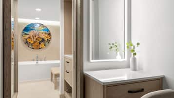 A modern bathroom with a bathtub, a vanity with a mirror, and a wall-mounted sink.