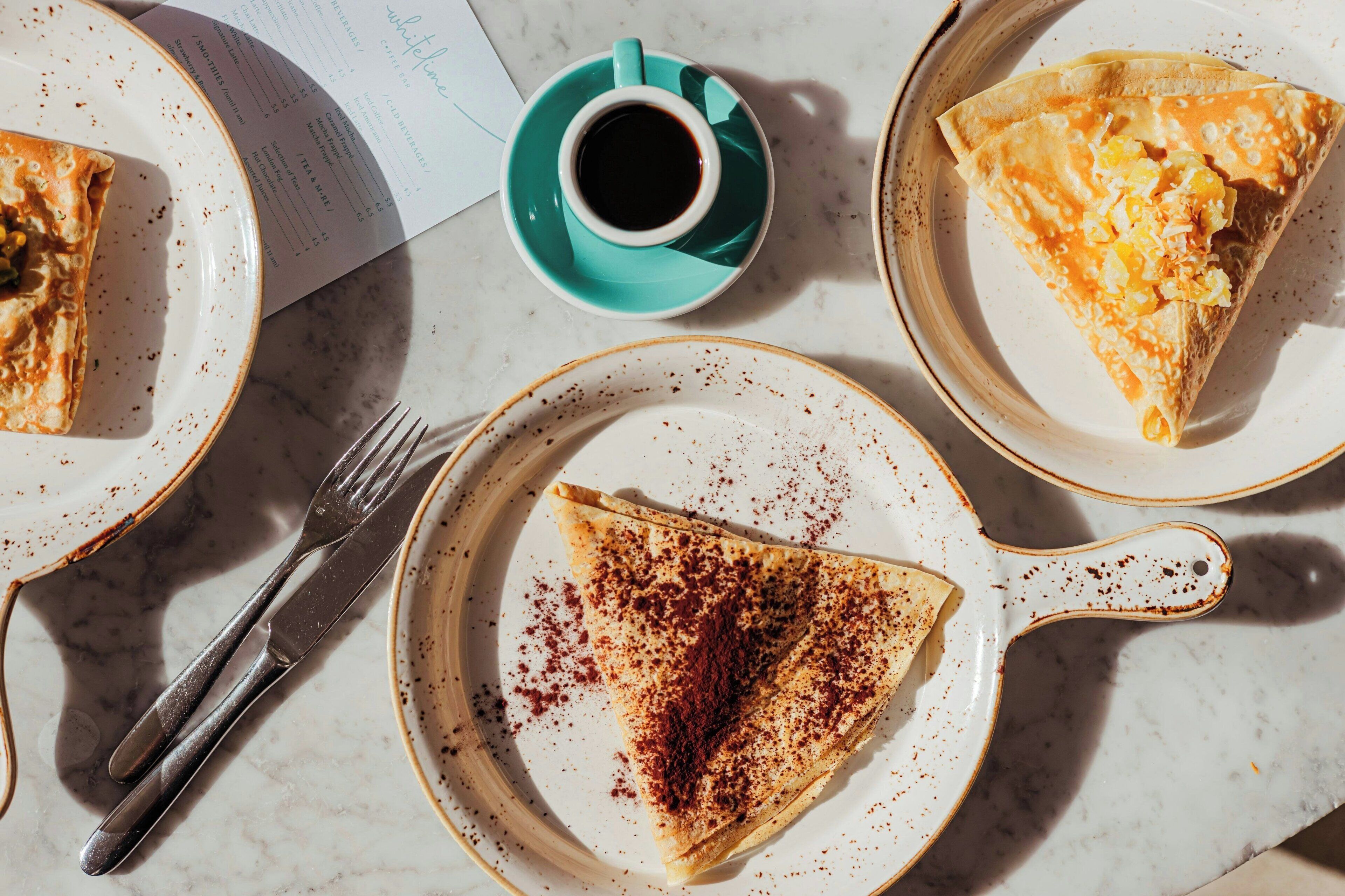 Un desayuno con una fuente de tortitas, una taza de café y un menú.