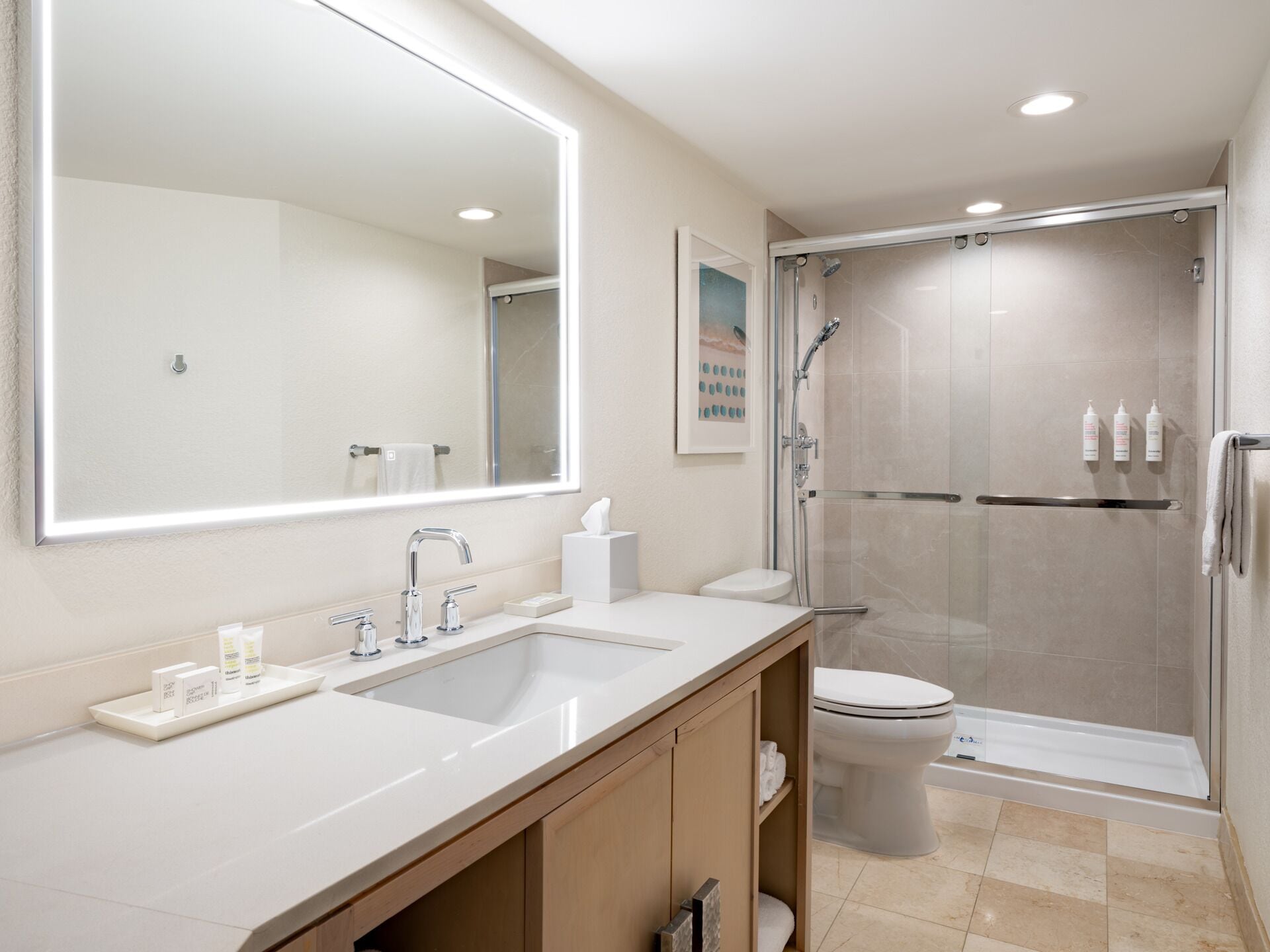 A modern bathroom with a large mirror, two sinks, a toilet, and a glass-enclosed shower.