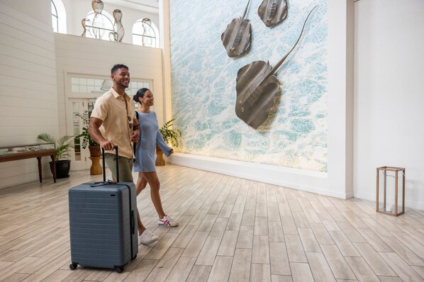 A spacious lobby with a large wall mural of fish, a wooden bench, and potted plants. - Grand Cayman Marriott Beach Resort (Seven Mile Beach)