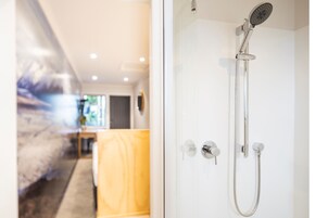 Un baño moderno con ducha, puerta de cristal y toalla amarilla.