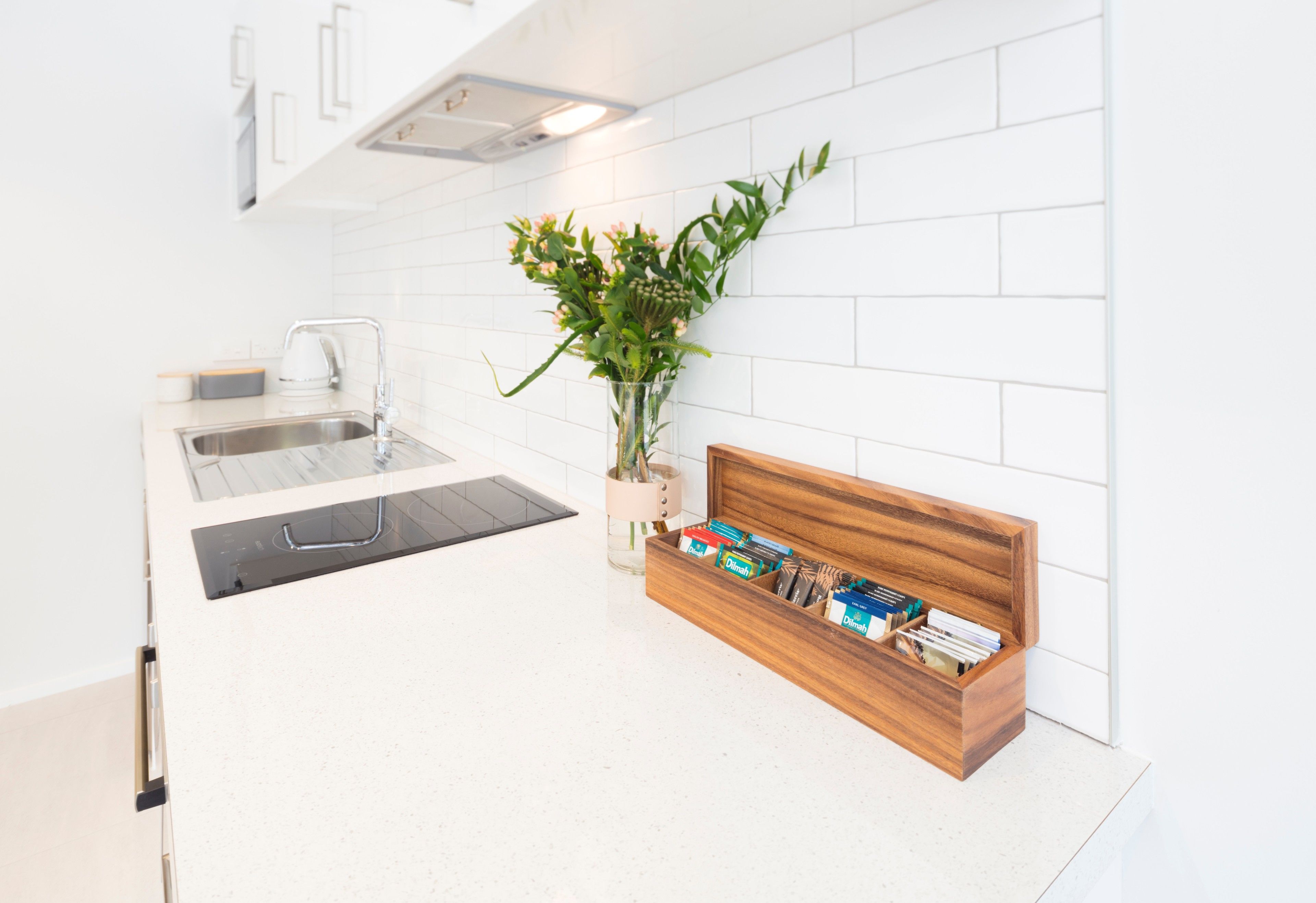 Cocina moderna con lavavajillas integrado, un lavabo y un mueble de madera con utensilios de cocina.