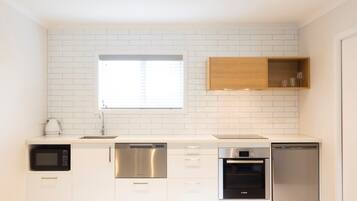 A modern kitchen with white subway tiles, stainless steel appliances, and a wooden upper cabinet.