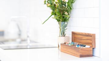 A kitchen with a wooden box containing various items, a vase with flowers, and a clear glass on the counter.